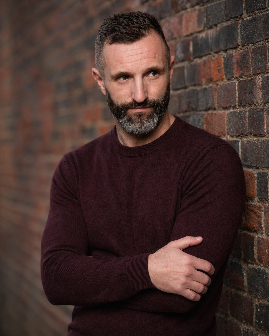 Wilson Meloncelli, portrait against a brick wall, dark maroon sweater